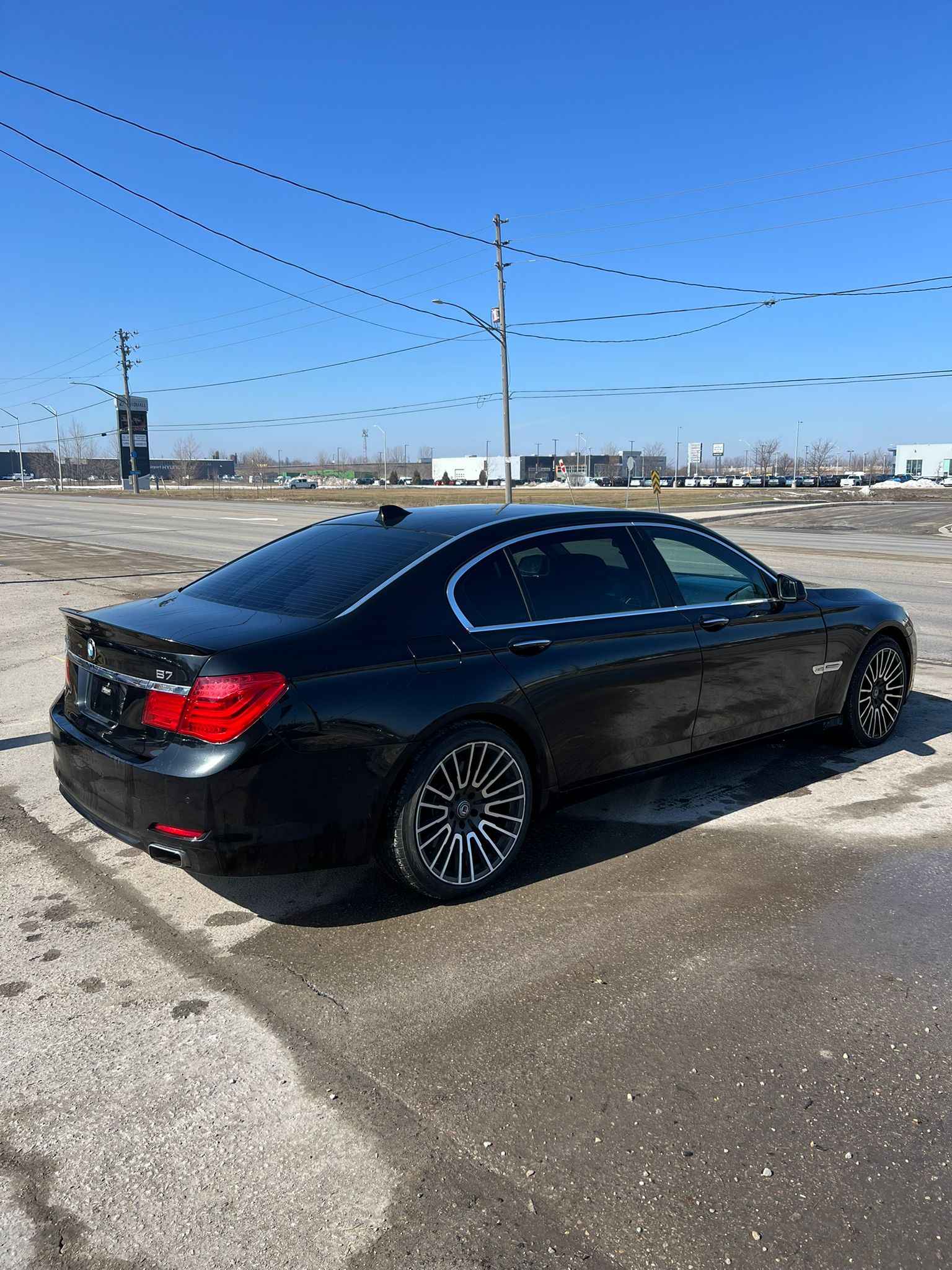 2012 BMW 750LI XDRIVE AWD 4DR BLACK rear three-quarter exterior view with multi-spoke alloy wheels in an open parking lot.