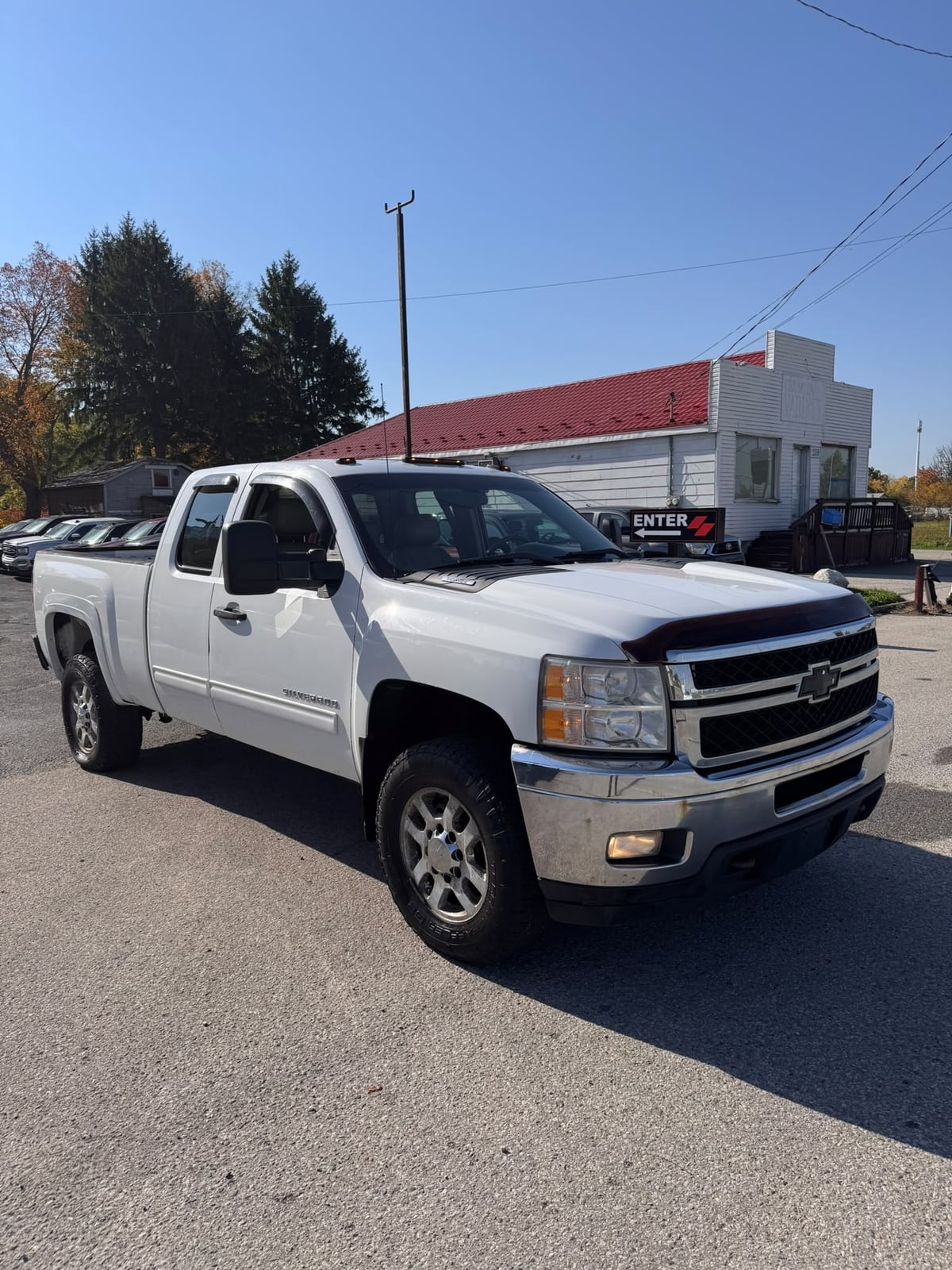 2011 Chevrolet SILVERADO 2500HD LTZ 4WD EXTENDED CAB REG BOX White front three-quarter exterior view with alloy wheels in dealership lot.