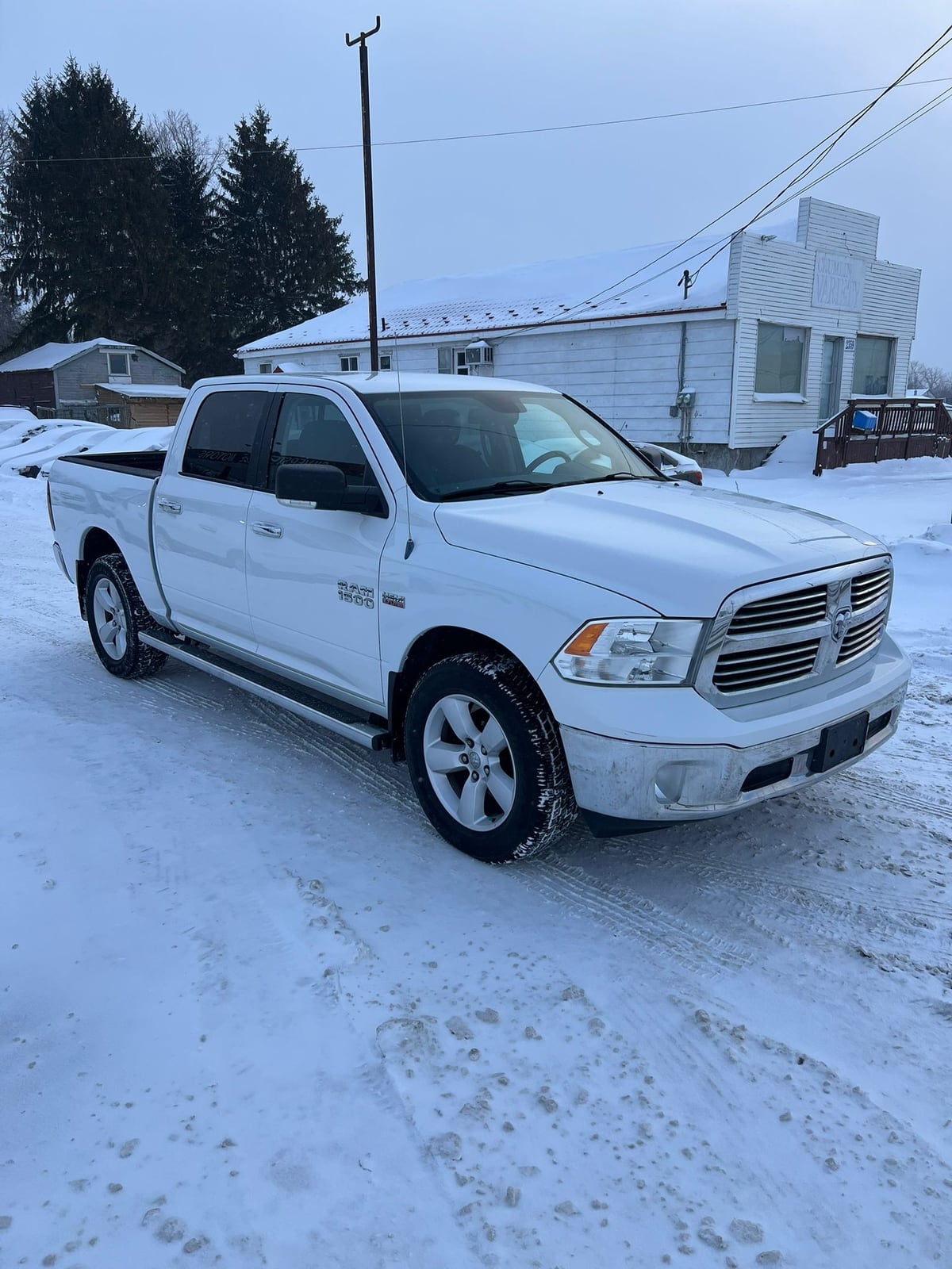 2013 RAM 1500 SLT CREW CAB 4WD SHORT BOX 140.5″ White front three-quarter exterior view parked in snowy driveway with chrome grille and alloy wheels.
