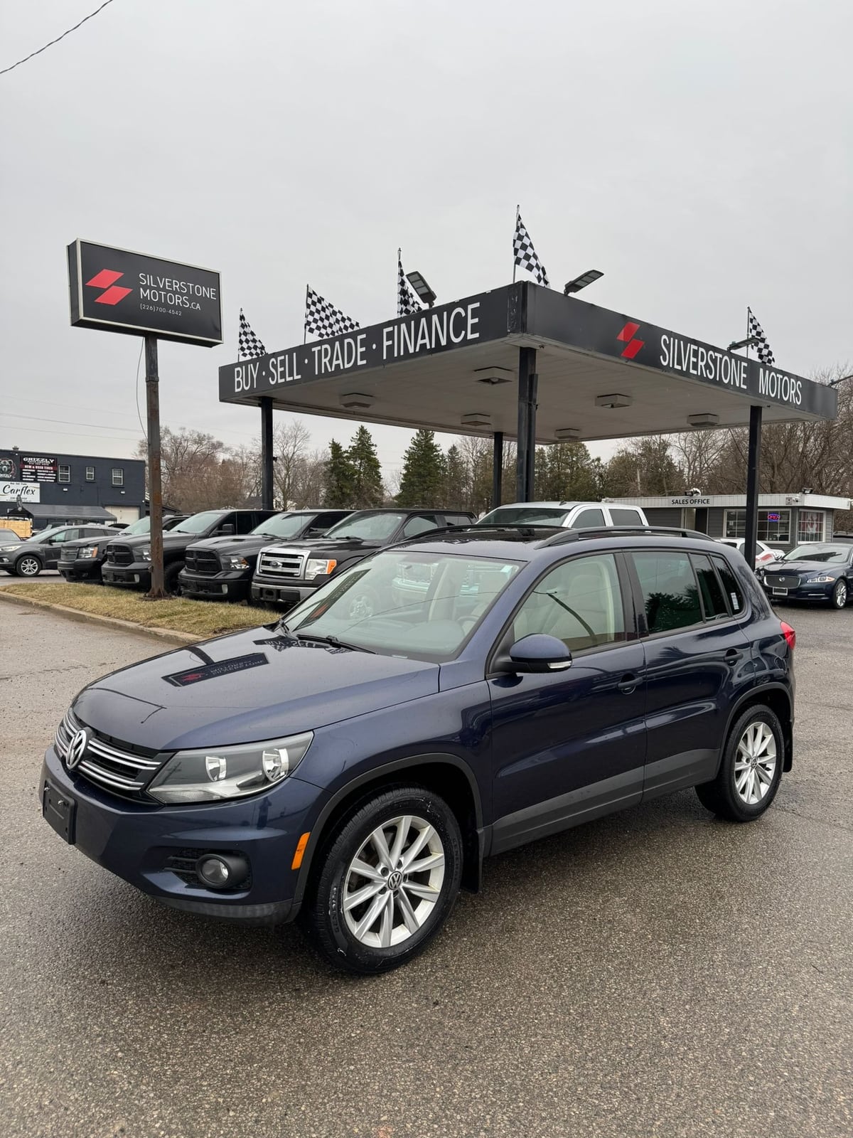 2015 VOLKSWAGEN TIGUAN HIGHLINE 4MOTION 4DR AUTO NAVY BLUE front three-quarter exterior view at dealership with silver alloy wheels.