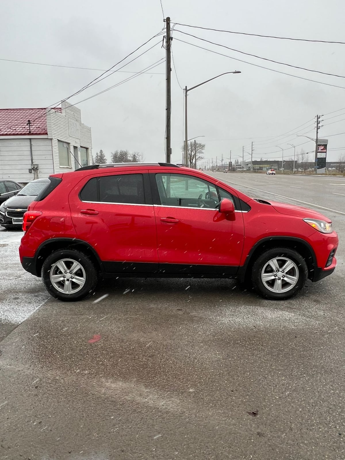 2017 Chevrolet TRAX LT AWD 4DR RED driver side exterior view with silver alloy wheels and black lower body cladding.