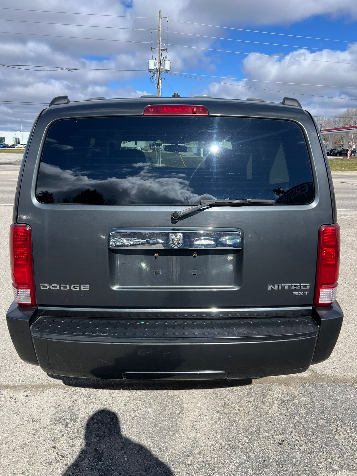 2010 Dodge Nitro SXT 4X4 4DR GREY rear exterior view showing taillights, badging, and tinted rear windows in daylight.