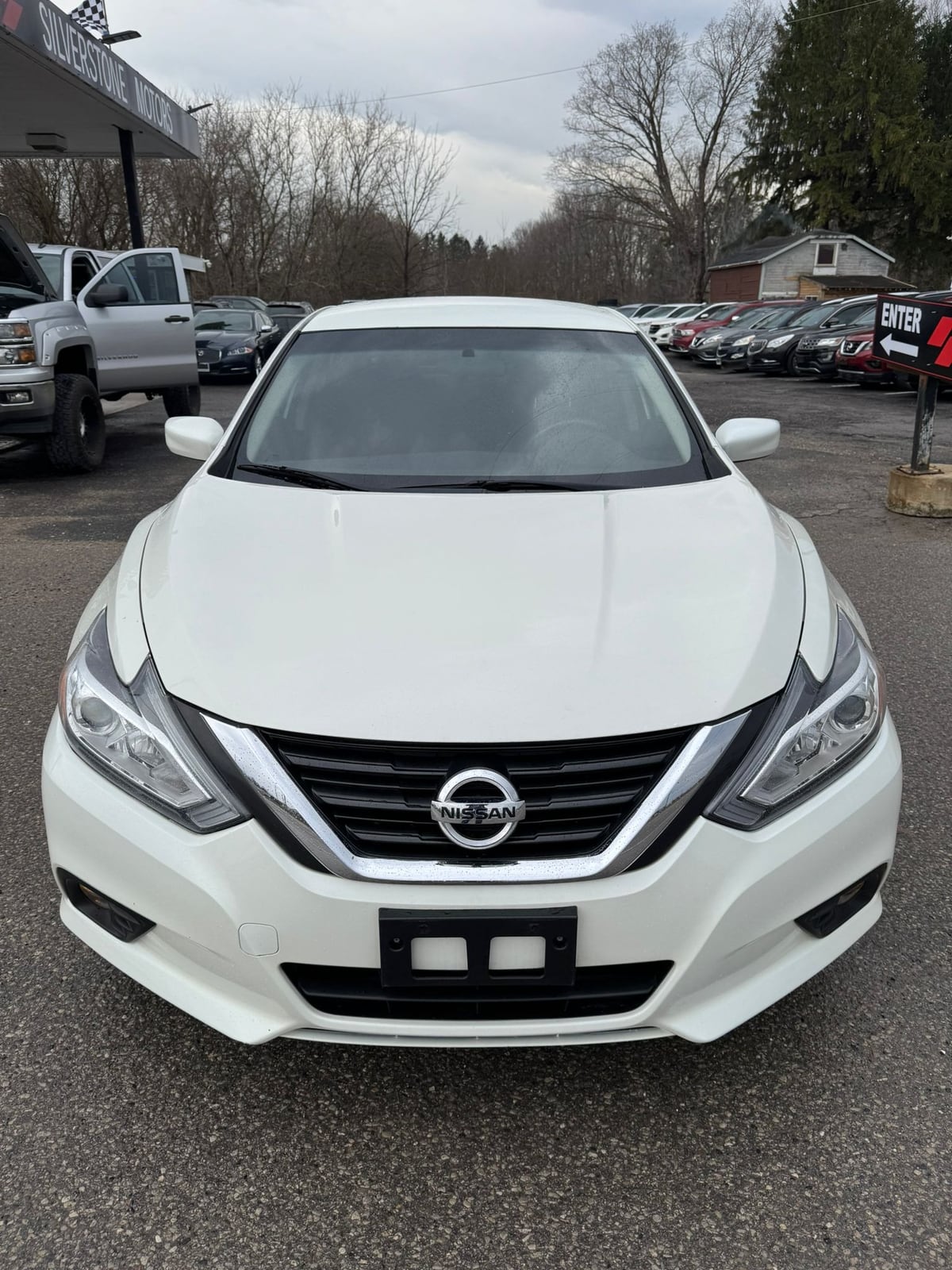 2018 Nissan ALTIMA SV 2.5 4DR White front exterior view showing chrome grille, white mirror caps, and headlights in dealer lot.