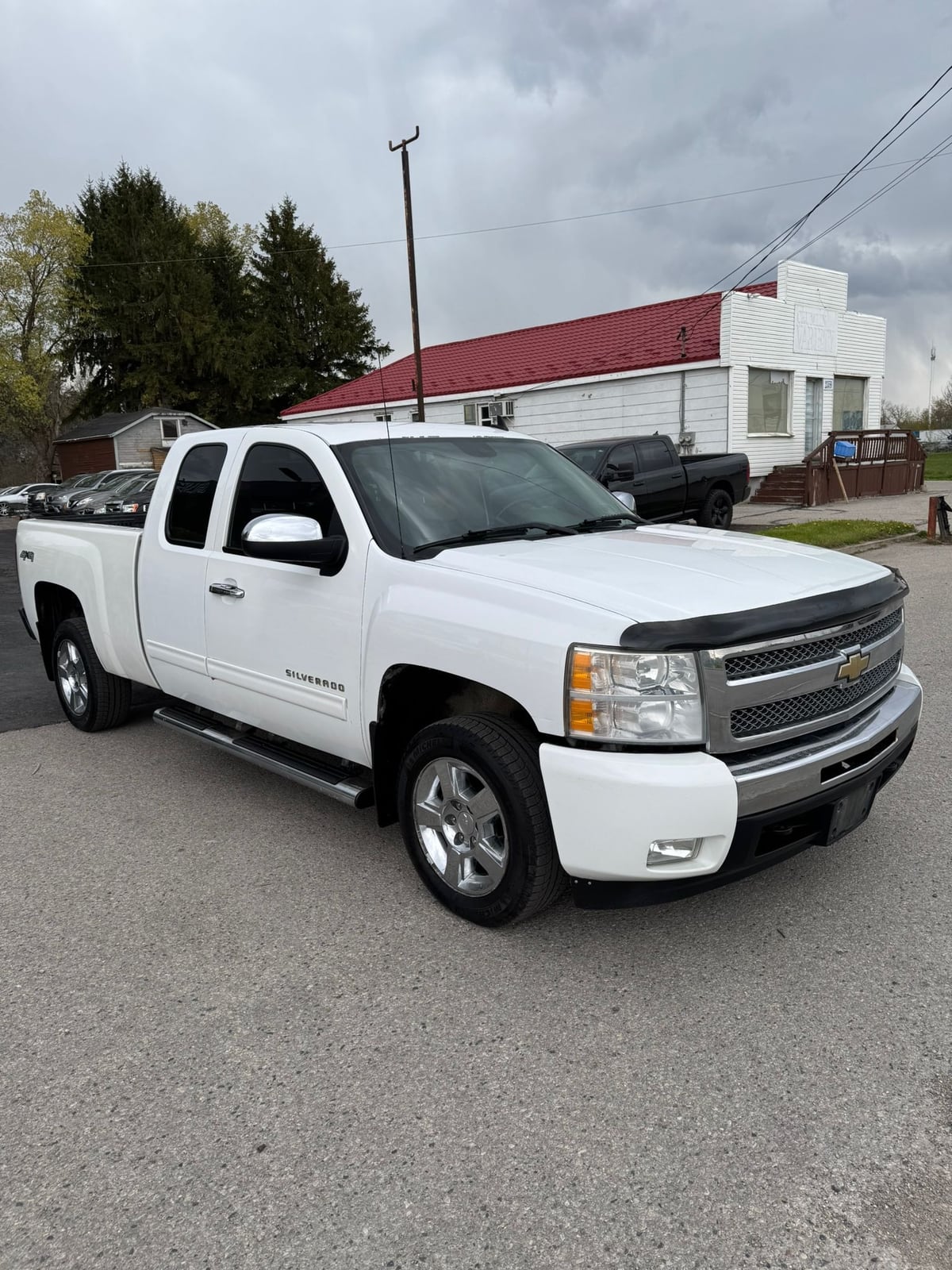 2011 Chevrolet SILVERADO LTZ 4WD EXTENDED CAB STANDARD BOX White front three-quarter exterior view with chrome grille and polished alloy wheels.