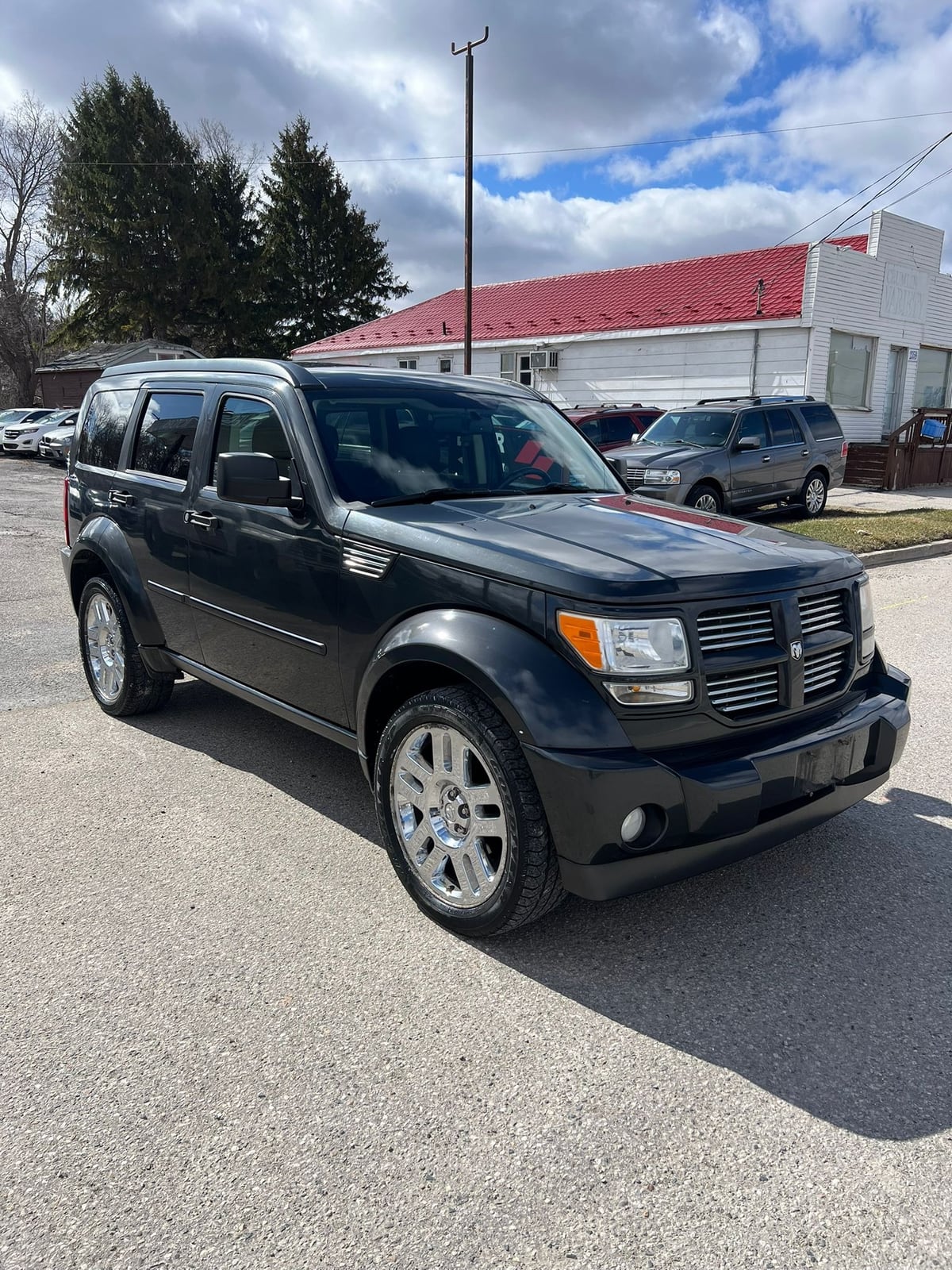 2010 Dodge Nitro SXT 4X4 4DR GREY front three-quarter exterior view with chrome alloy wheels and horizontal grille design.