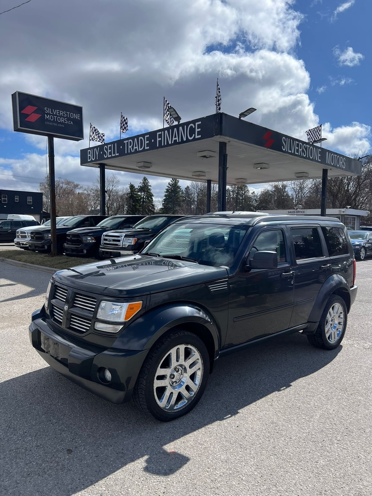 2010 Dodge Nitro SXT 4X4 4DR GREY front three-quarter exterior view with chrome alloy wheels at dealership lot under canopy.