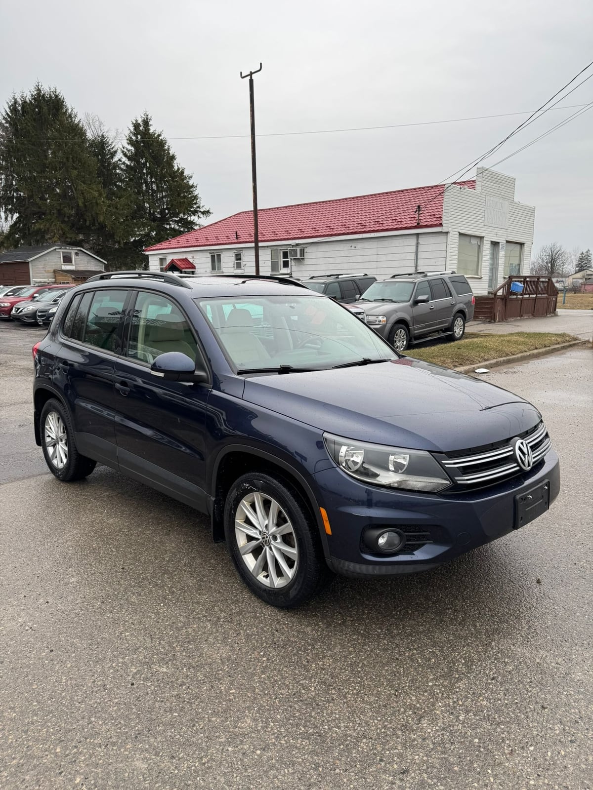 2015 VOLKSWAGEN TIGUAN HIGHLINE 4MOTION 4DR AUTO NAVY BLUE front three-quarter exterior view with silver alloy wheels in dealership lot.