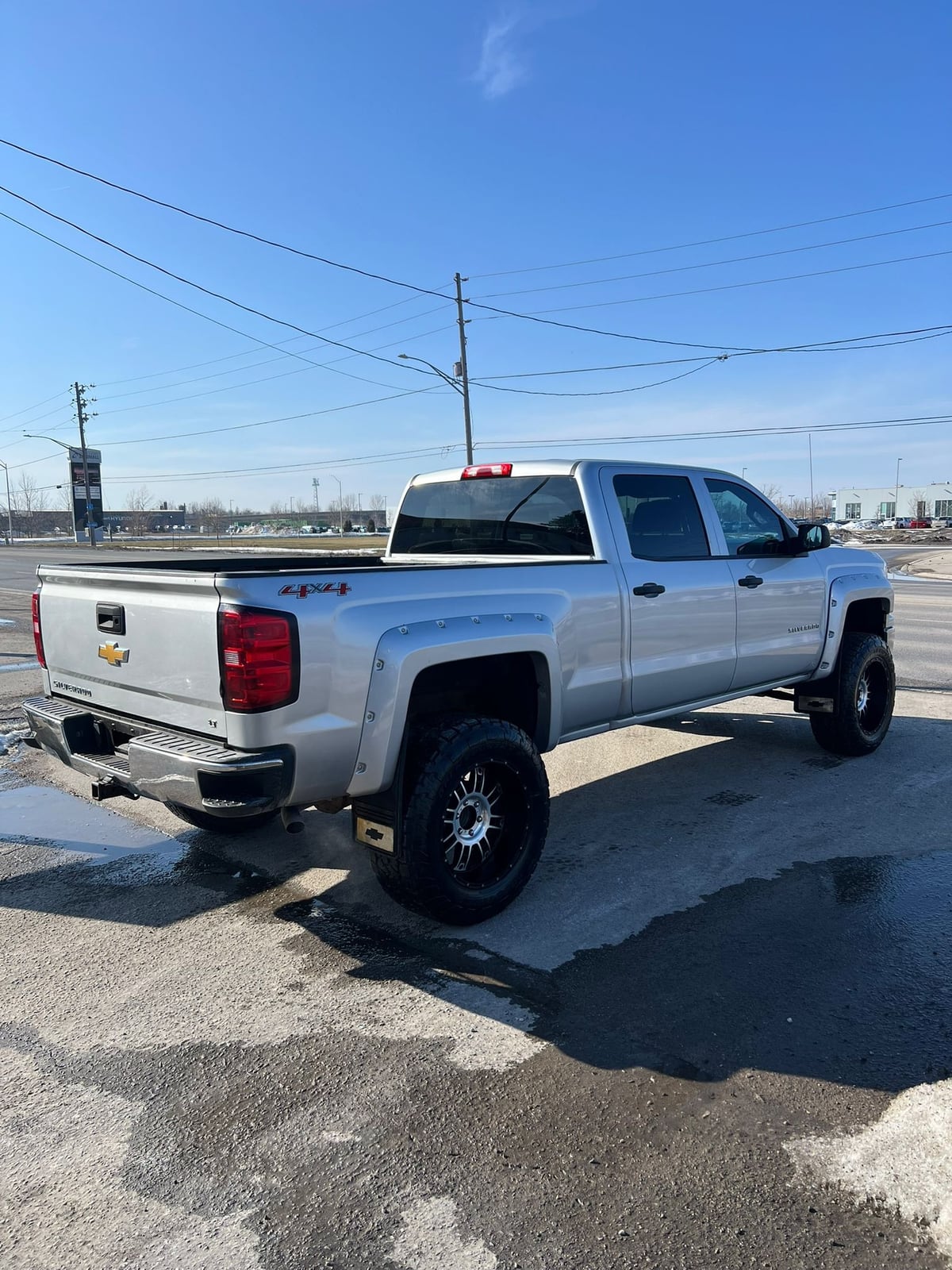 2014 Chevrolet SILVERADO 1500 LT w/1LT 4WD CREWCAB SILVER rear three-quarter exterior view showing bed, chrome accents, and decorative wheel trim.
