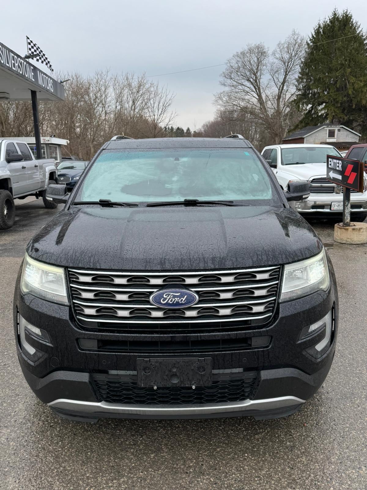 2016 Ford Explorer XLT 4WD 4DR BLACK front exterior view with light blue sunshade and checkered flag dealership sign visible.