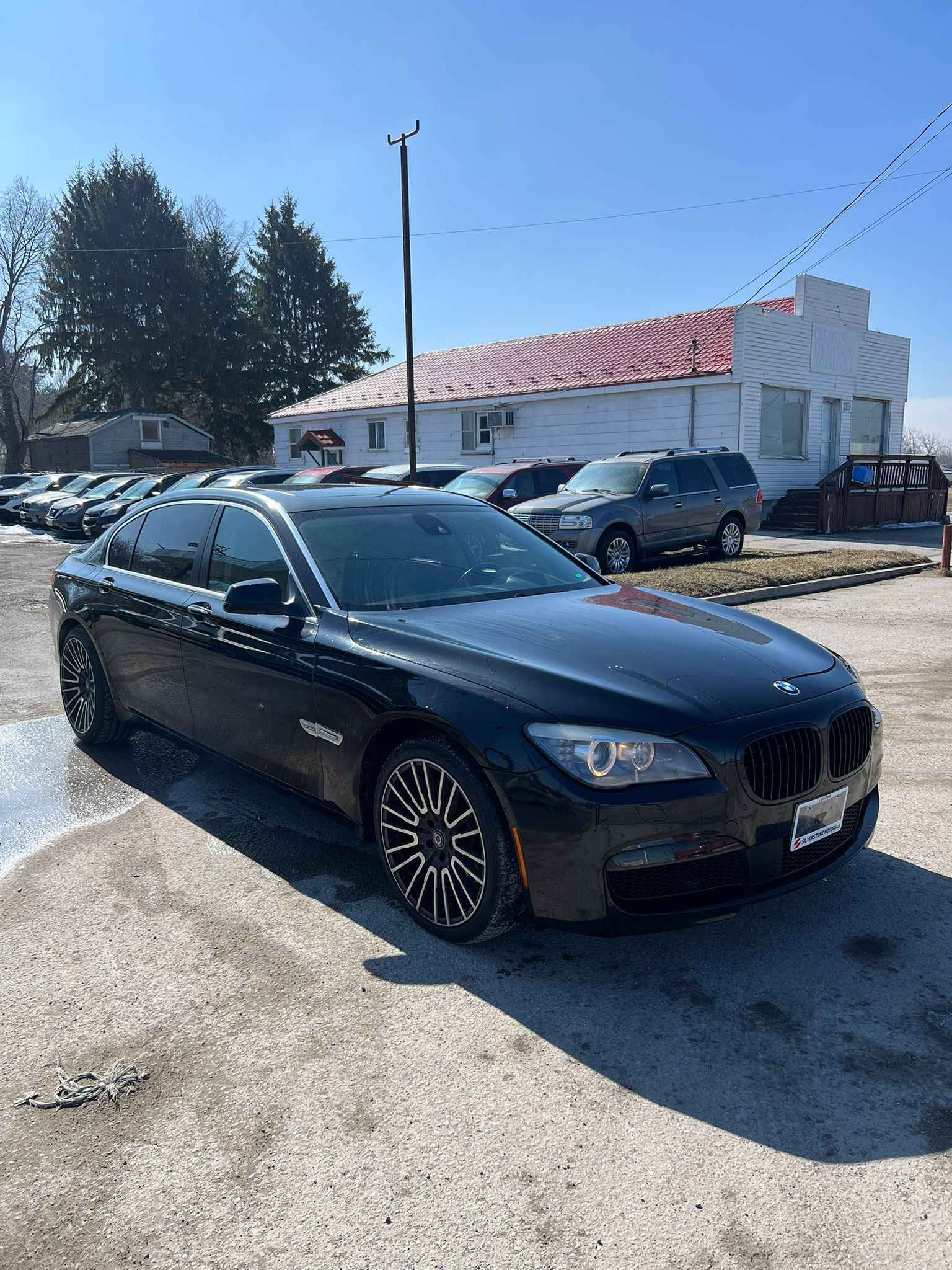 2012 BMW 750LI XDRIVE AWD 4DR BLACK front three-quarter exterior view with multi-spoke alloy wheels in dealership lot setting.