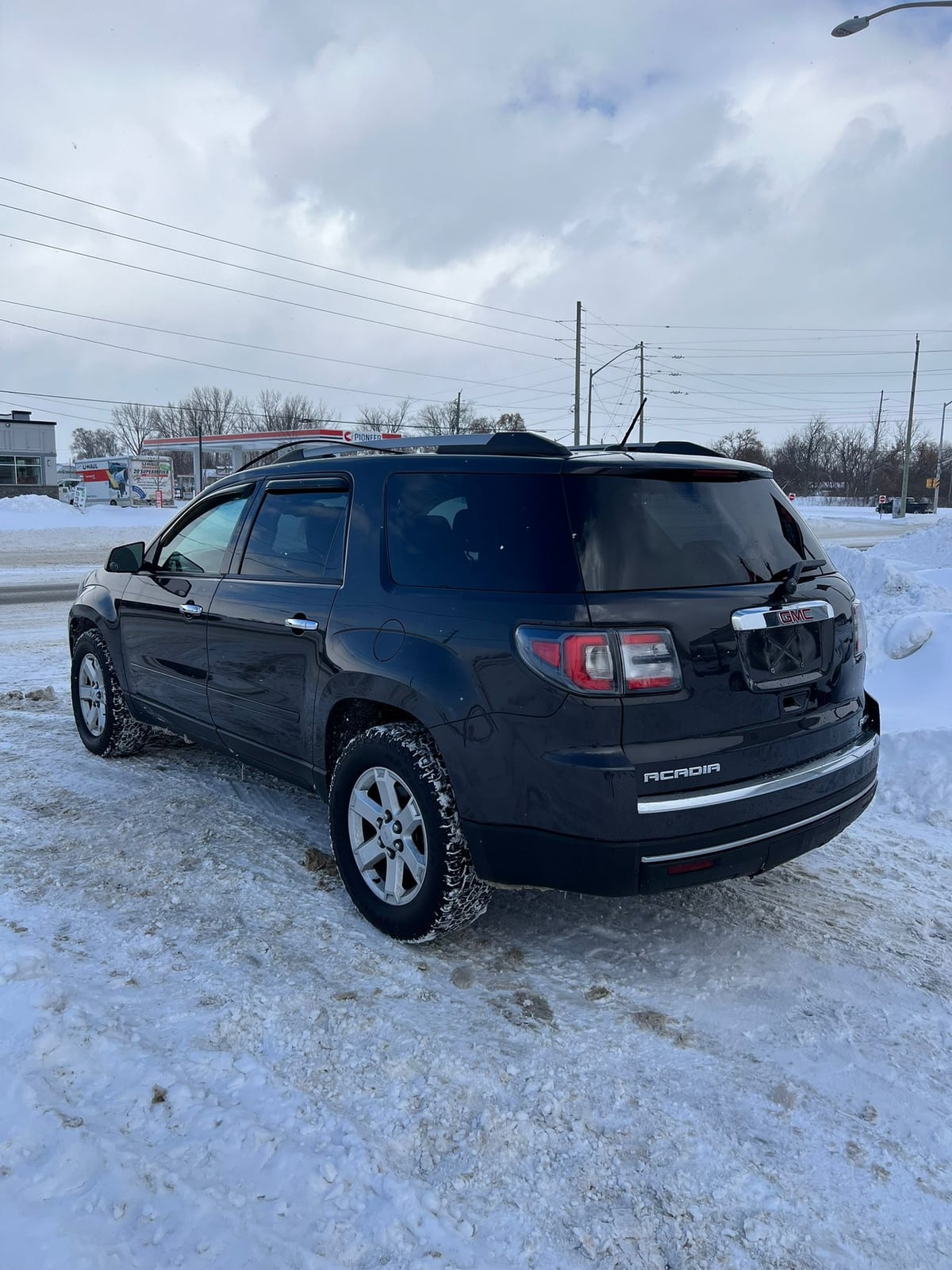 2015 GMC ACADIA SLE AWD 4DR GRAY rear three-quarter exterior view with alloy wheels in snowy parking lot setting.