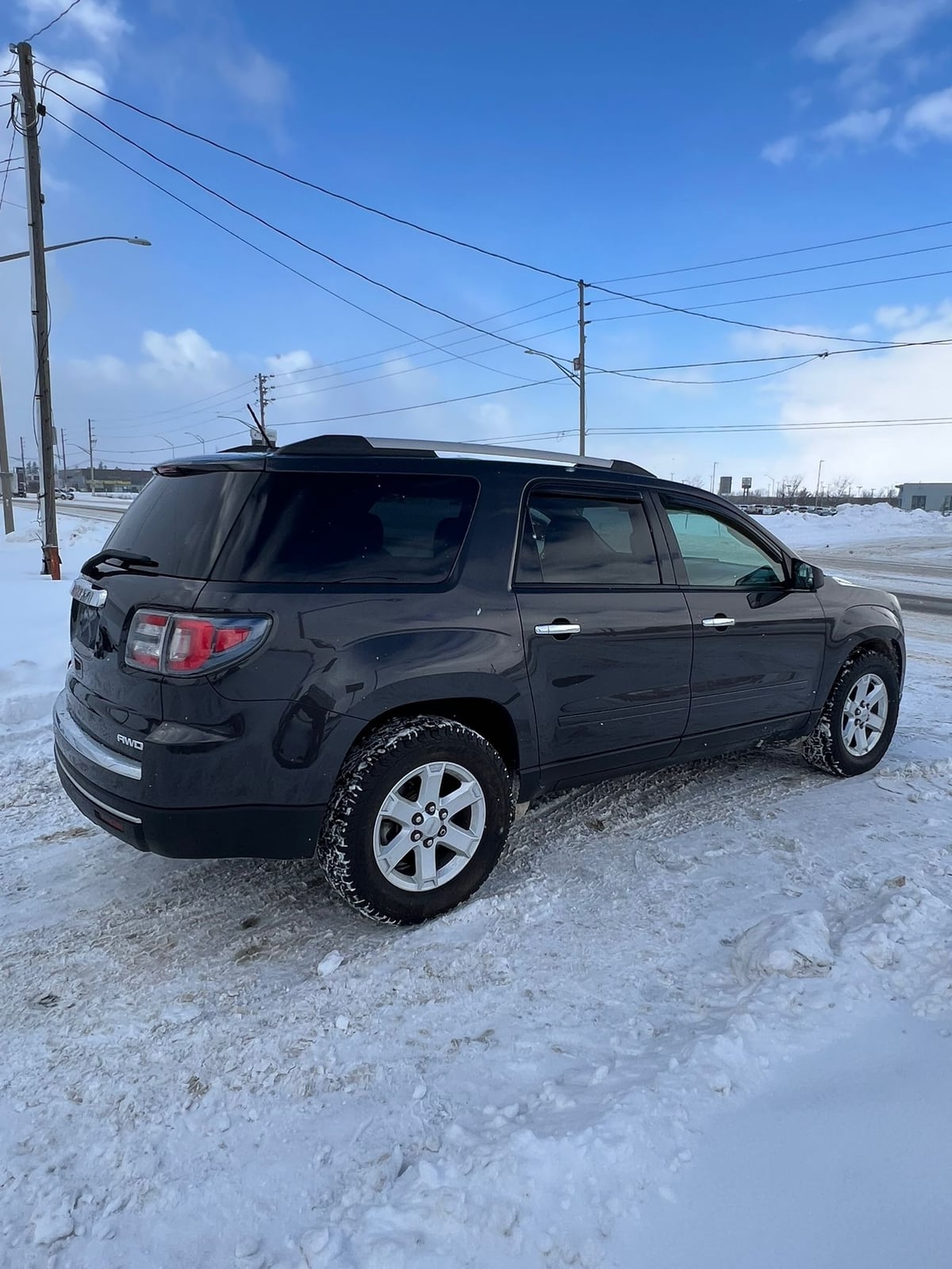 2015 GMC ACADIA SLE AWD 4DR GRAY side exterior view parked in snow with alloy wheels and tinted windows visible.