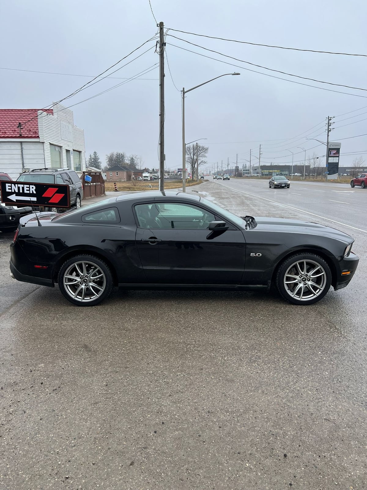 2012 Ford MUSTANG GT 5.0L COUPE 2DR BLACK driver side exterior view with polished alloy wheels in dealership lot.