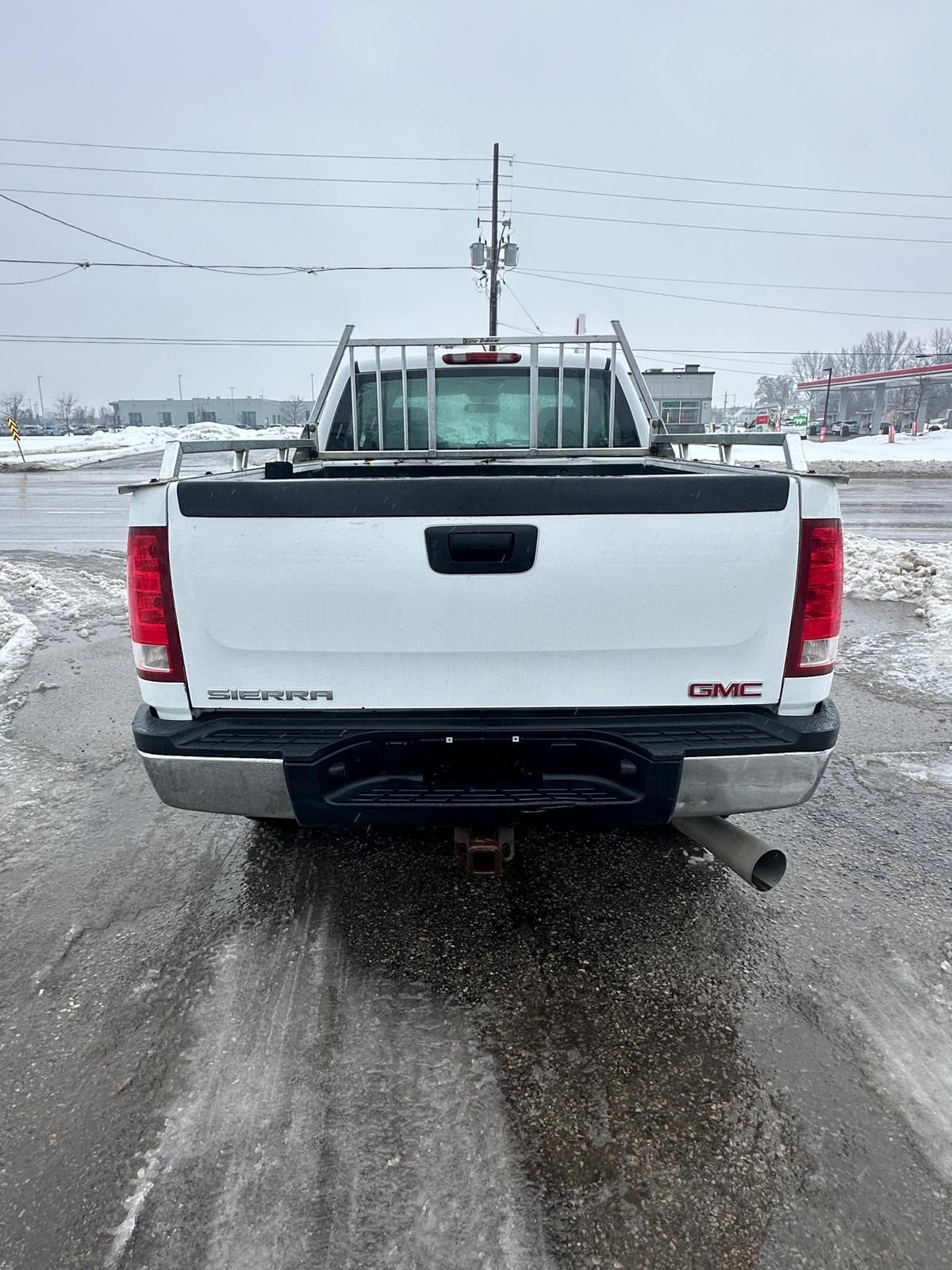 2007 GMC 2500HD DURAMAX DIESEL SIERRA 2500HD 6.6 DURMAX DIESEL WT EXTENDED CAB STD White rear exterior view with truck bed and window guard visible.