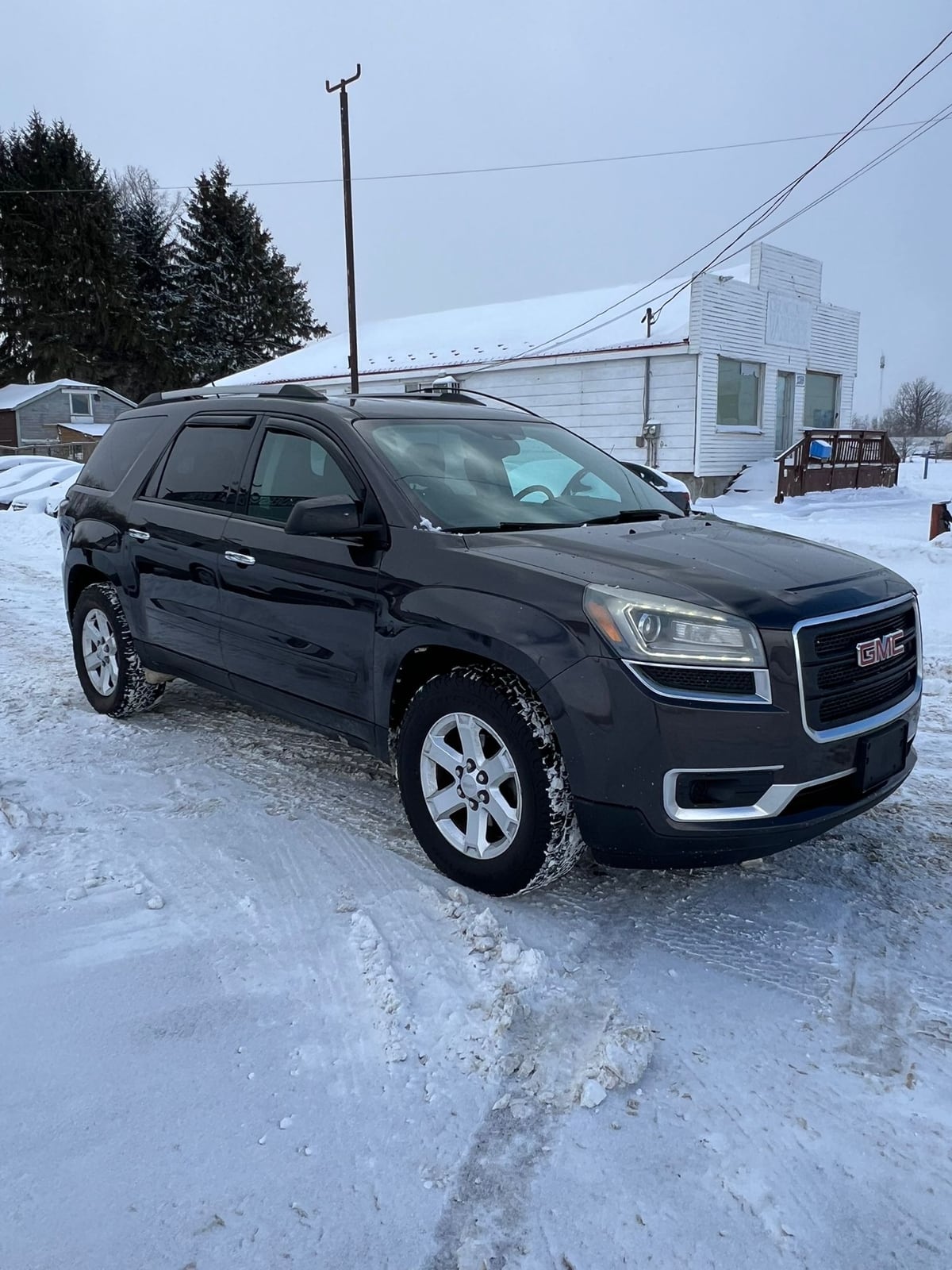 2015 GMC ACADIA SLE AWD 4DR GRAY front three-quarter exterior view parked in snowy driveway with silver alloy wheels.