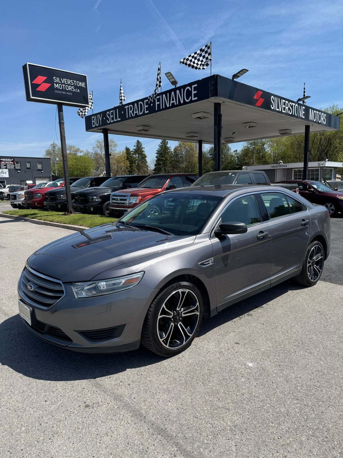 2014 Ford TAURUS SE FWD 4DR GRAY front three-quarter exterior view at Silverstone Motors dealership with alloy wheels.