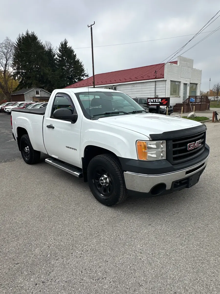 2011 GMC Sierra LS REGULAR CAB SHORT BOX White front three-quarter exterior view with chrome grille and silver wheels in dealership lot.