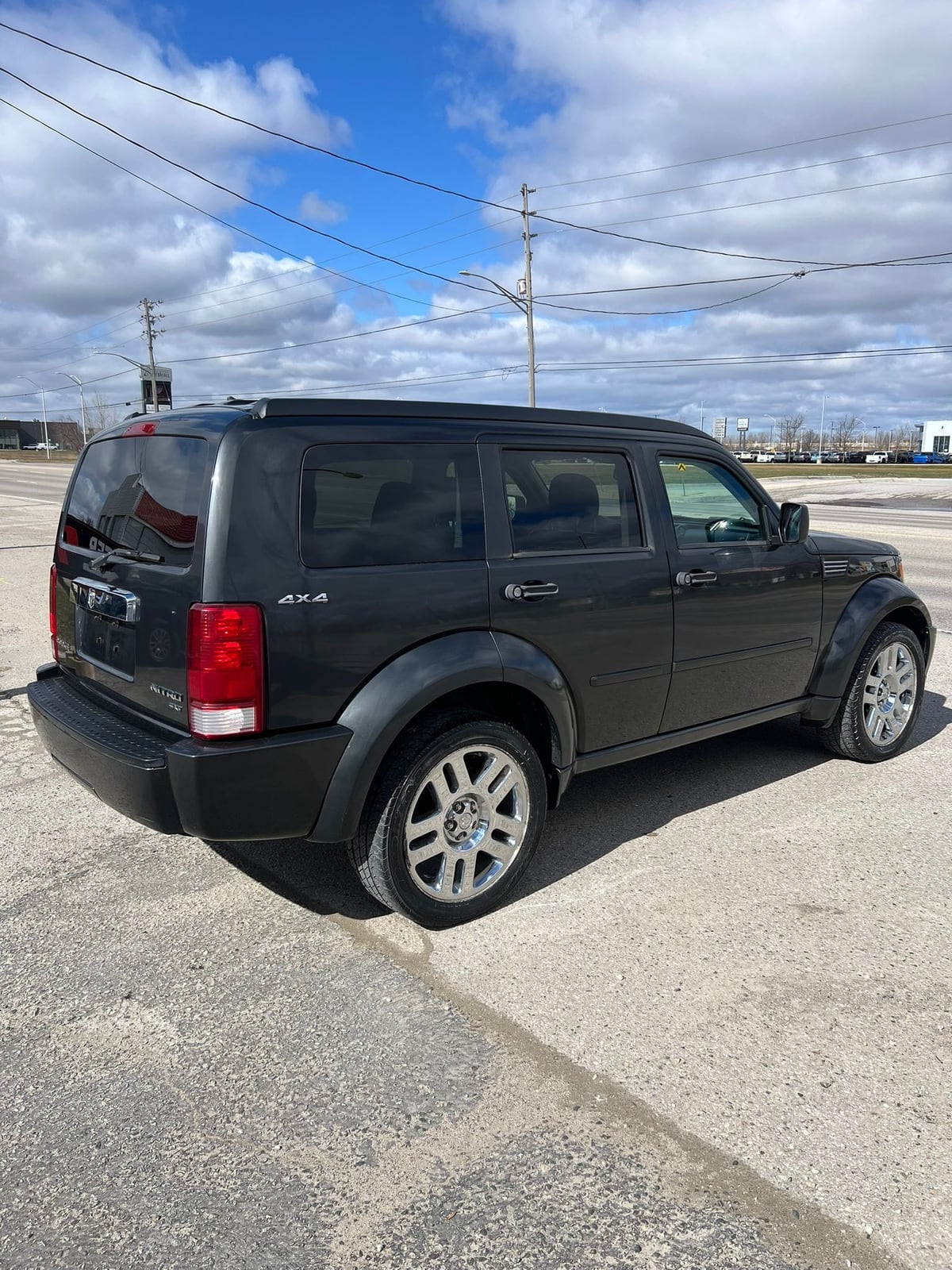2010 Dodge Nitro SXT 4X4 4DR GREY, rear three-quarter exterior view showing chrome alloy wheels and red taillights.