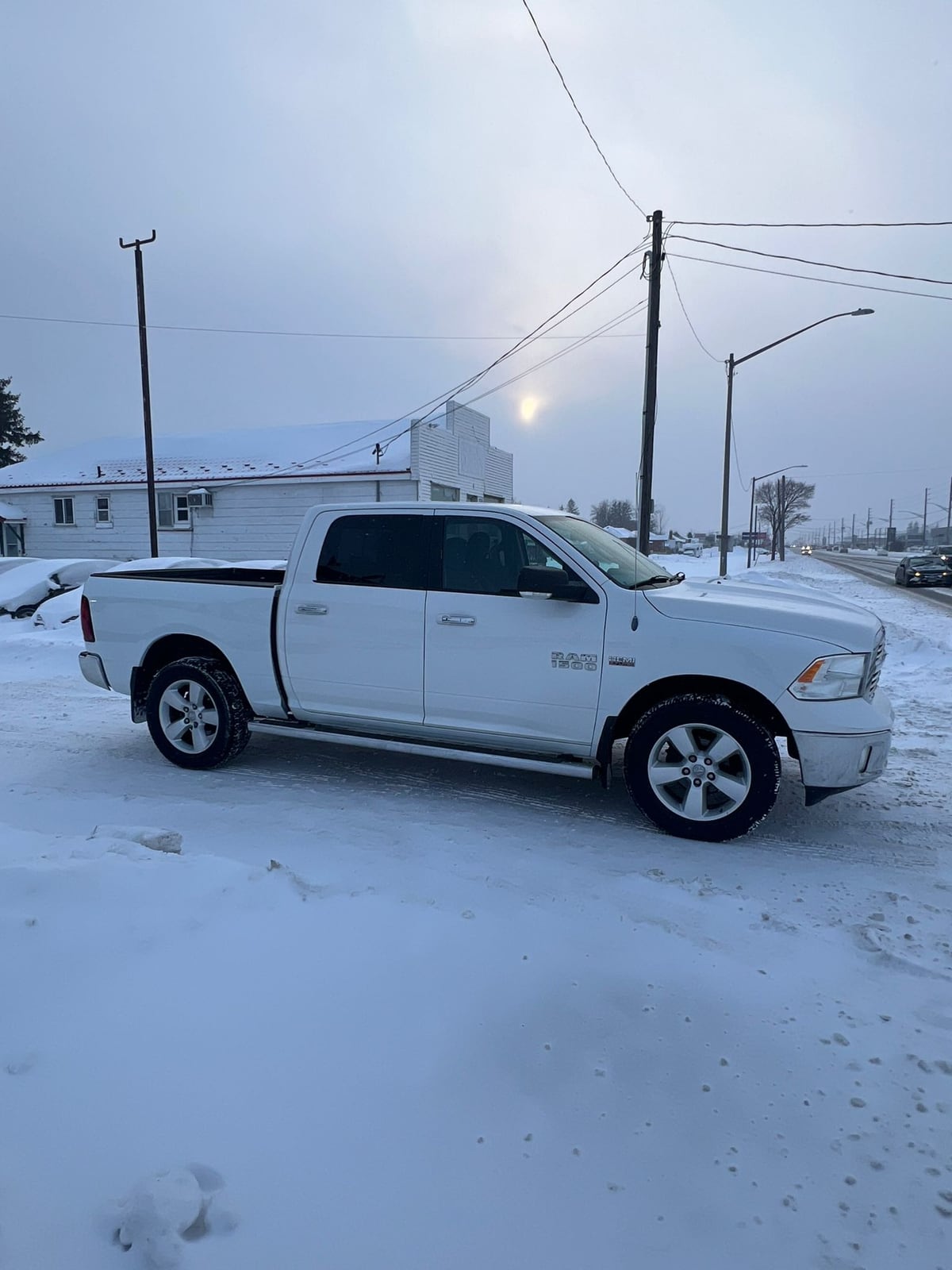 2013 RAM 1500 SLT CREW CAB 4WD SHORT BOX 140.5″ White shown in side profile view on snowy ground with chrome alloy wheels and winter setting.
