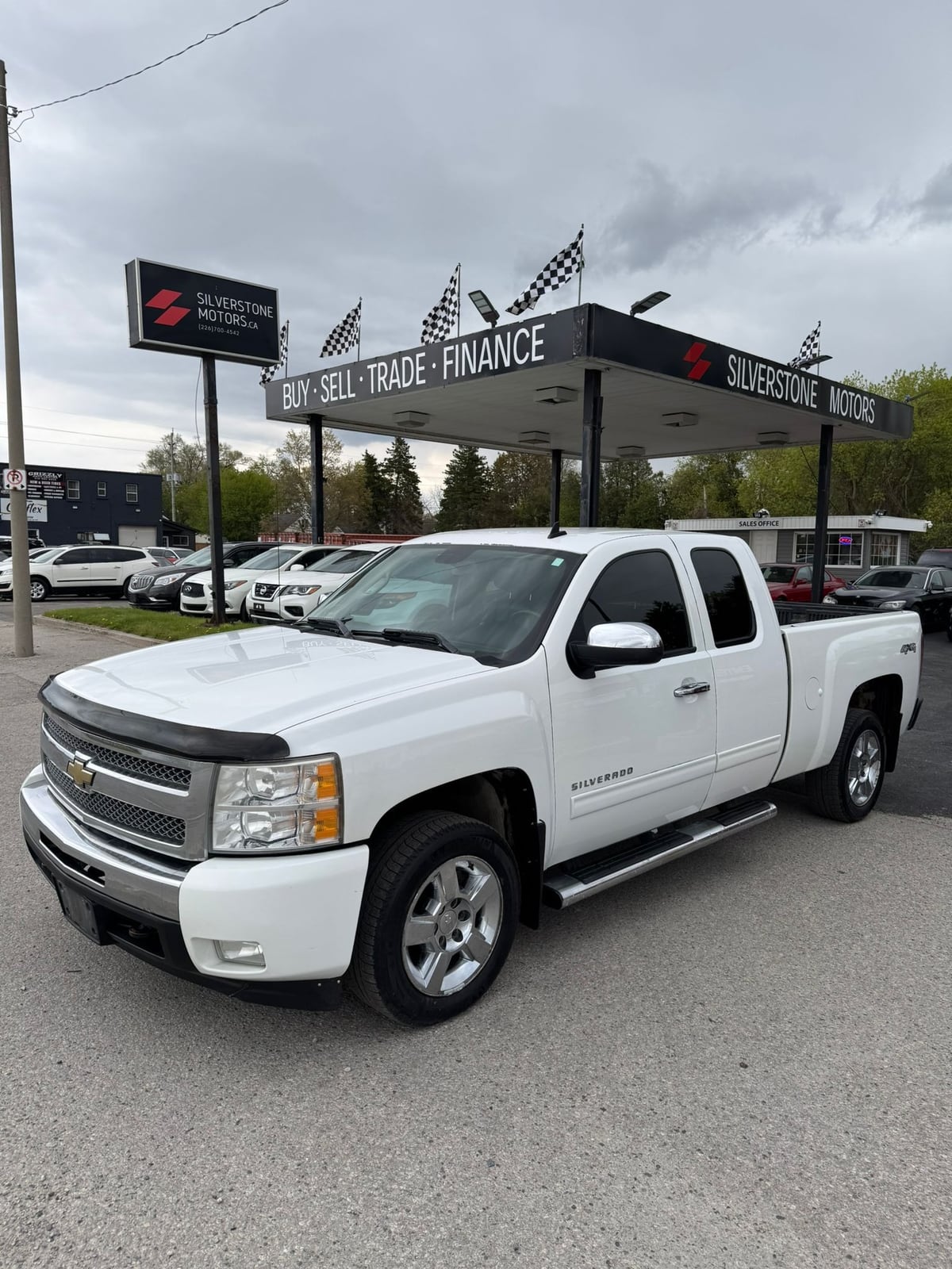 2011 Chevrolet SILVERADO LTZ 4WD EXTENDED CAB STANDARD BOX White front three-quarter exterior view at dealership with polished alloy wheels and chrome accents.