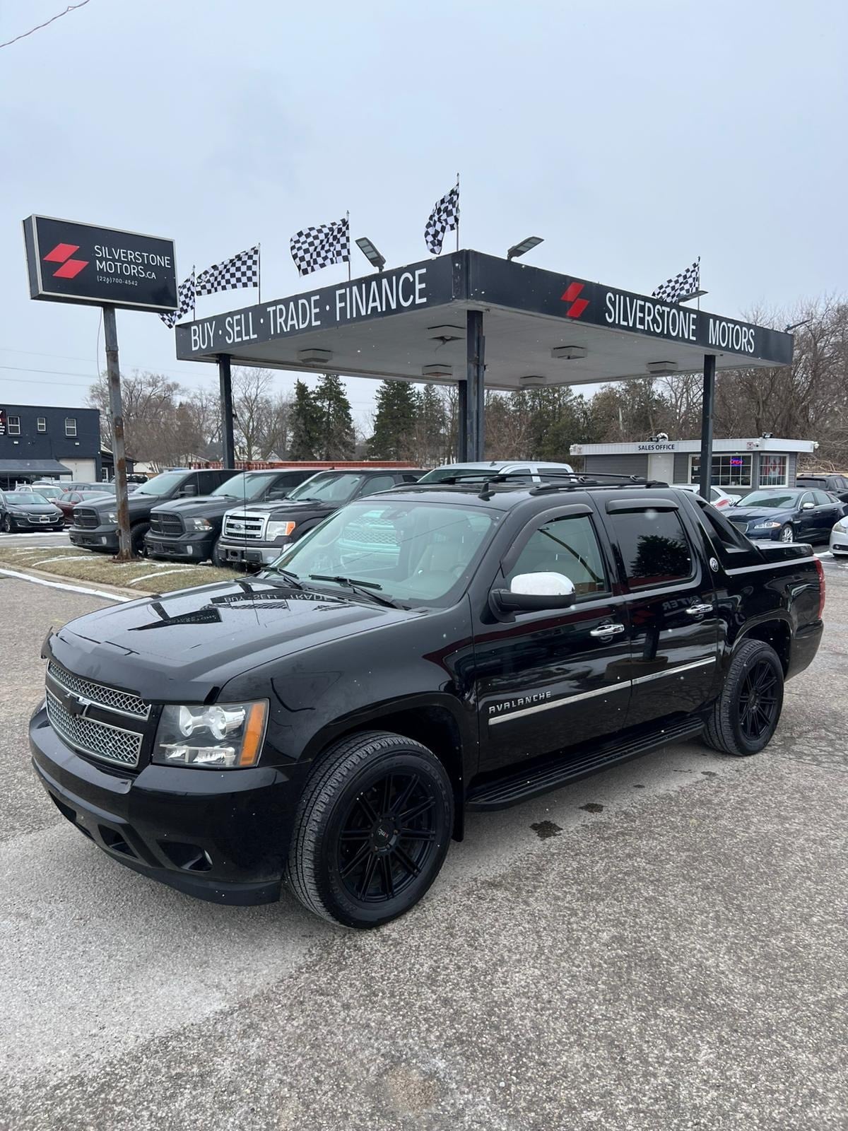 2013 Chevrolet Avalanche LTZ BLACK DIAMOND EDITION 4WD 4DR BLACK front three-quarter exterior view with black alloy wheels at dealership lot.