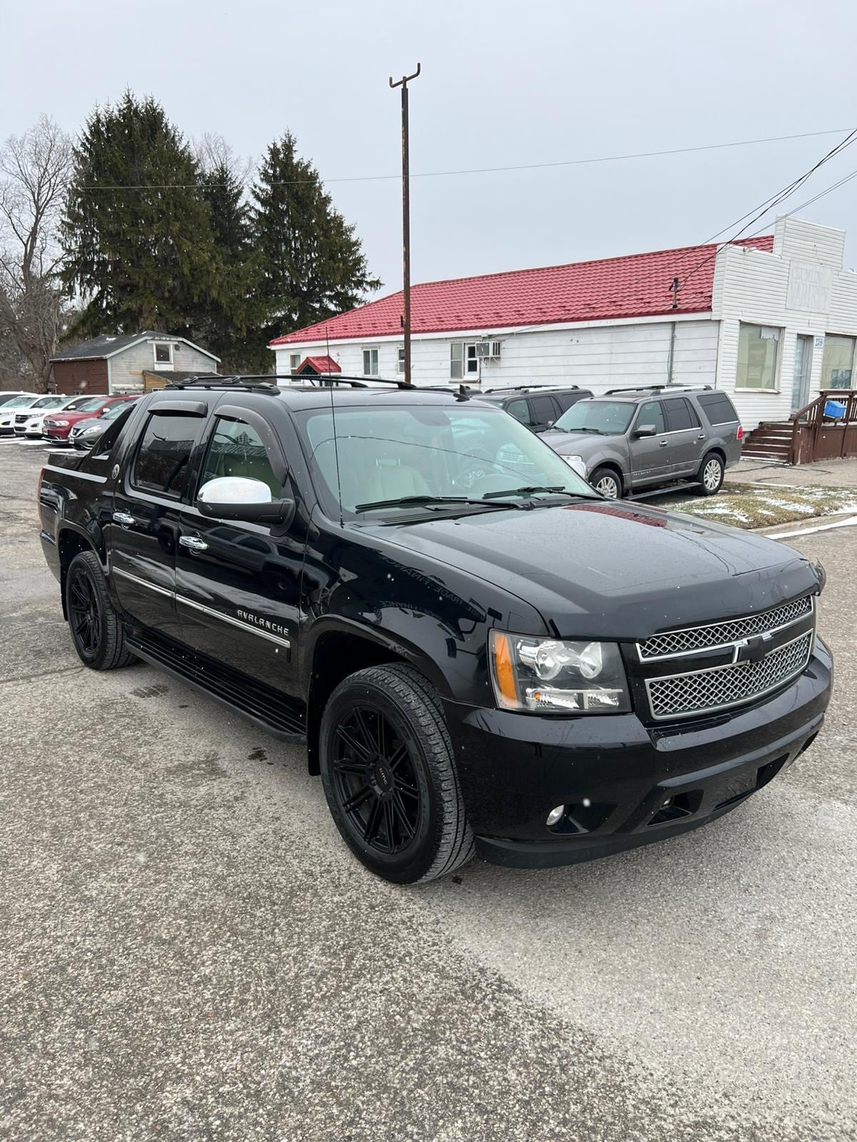 2013 Chevrolet Avalanche LTZ BLACK DIAMOND EDITION 4WD 4DR BLACK front three-quarter exterior view with black alloy wheels and white mirror caps.