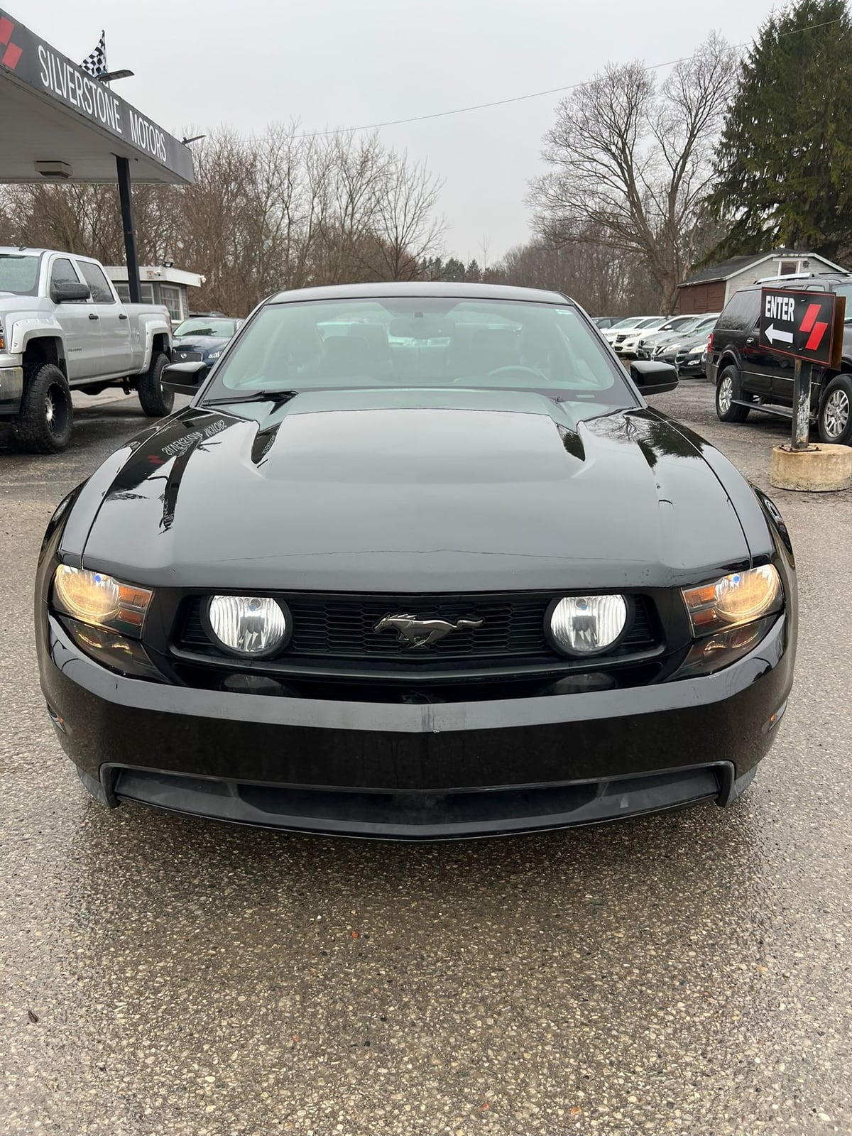2012 Ford MUSTANG GT 5.0L COUPE 2DR BLACK front exterior view with dual hood vents and illuminated headlights at dealership lot.