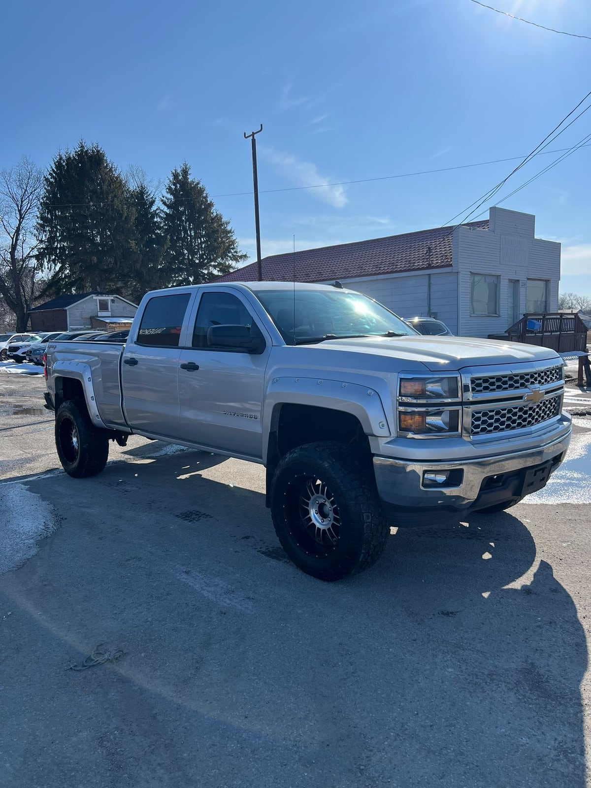 2014 Chevrolet SILVERADO 1500 LT w/1LT 4WD CREWCAB SILVER front three-quarter exterior view with custom chrome wheels and lifted suspension in dealership lot.