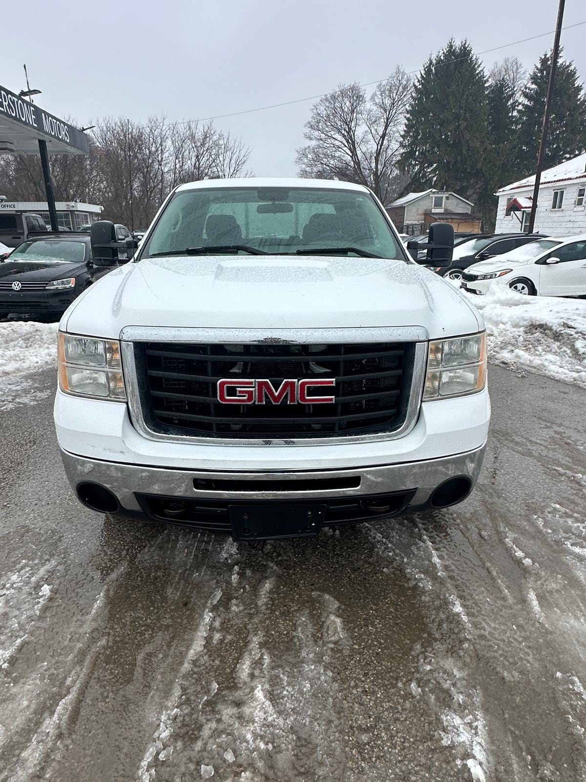 2007 GMC 2500HD DURAMAX DIESEL SIERRA 2500HD 6.6 DURMAX DIESEL WT EXTENDED CAB STD White front exterior view with GMC badging and dual exhaust visible in snowy dealership lot.