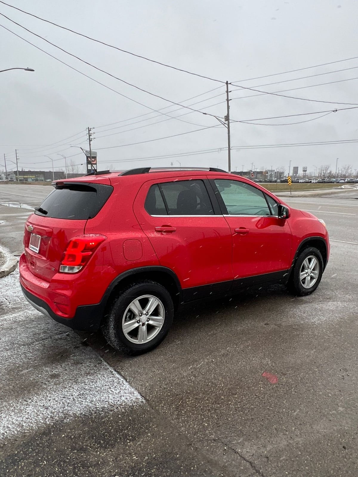 2017 Chevrolet TRAX LT AWD 4DR RED driver side exterior view with silver alloy wheels on overcast day.