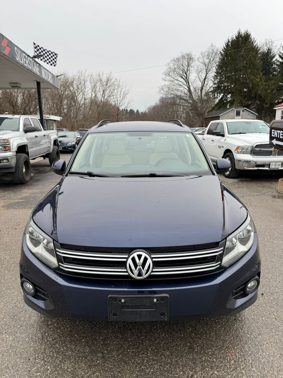 2015 VOLKSWAGEN TIGUAN HIGHLINE 4MOTION 4DR AUTO NAVY BLUE front exterior view in dealership lot with checkered flag signage.